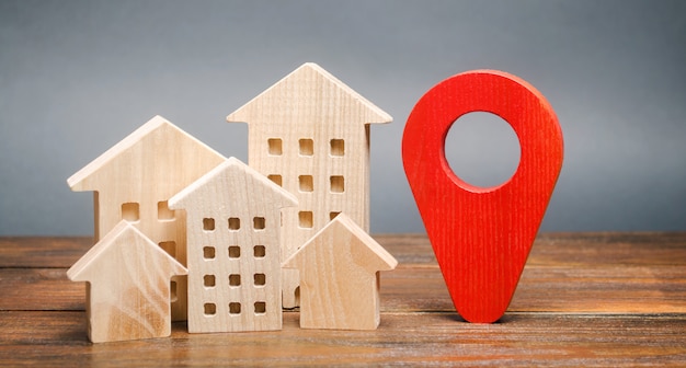 Maisons en bois miniatures et marqueur de géolocalisation. Emplacement des bâtiments résidentiels.