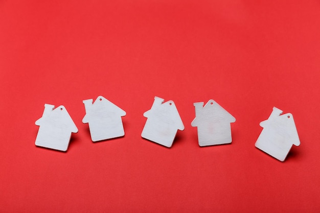 Maisons de jouets peintes en blanc dansant sur fond rouge. Notion d'immobilier