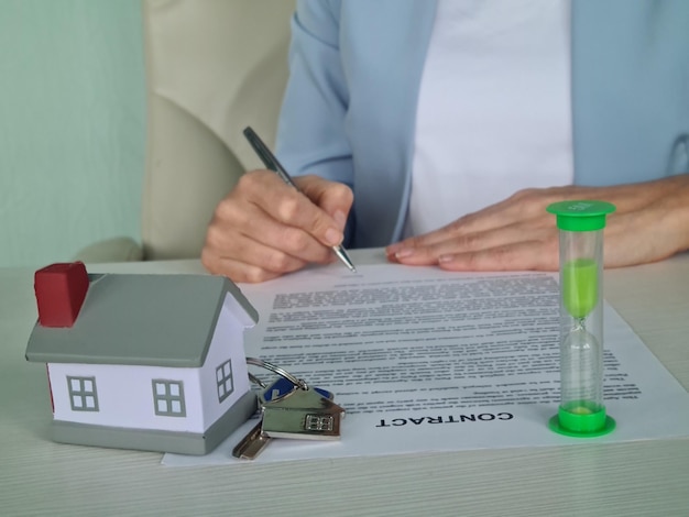 Des maisons modèles et des documents de contrat sur la table dans le bureau la femme prend la décision