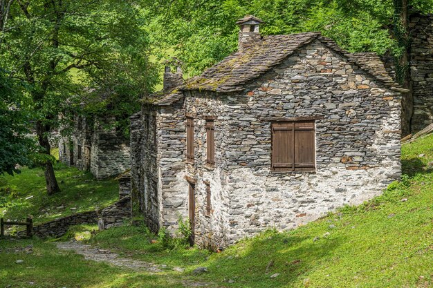 Photo des maisons et des moulins en pierre en ruine dans un village de montagne abandonné dans les alpes