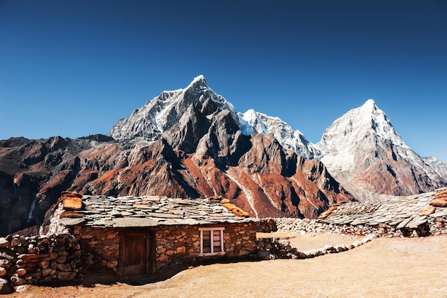 Maisons népalaises traditionnelles et vue sur les pics Taboche et Cholatse dans les montagnes de l'Himalaya. Vallée du Khumbu, région de l'Everest, Népal.