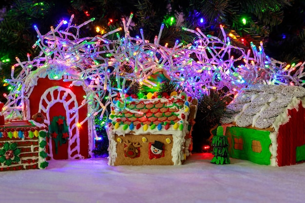 Des maisons en pain d'épice avec des guirlandes colorées et un arbre de Noël