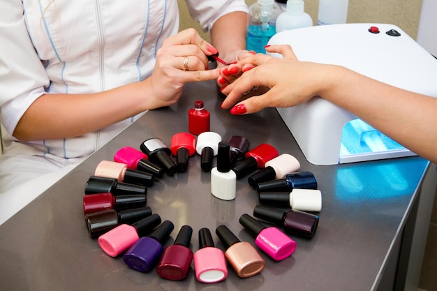 Photo le maître applique du vernis gel sur les ongles dans un salon de manucure