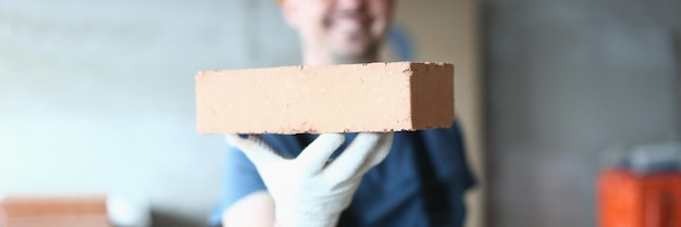 Un maître bâtisseur tenant une brique rouge sur un chantier de construction