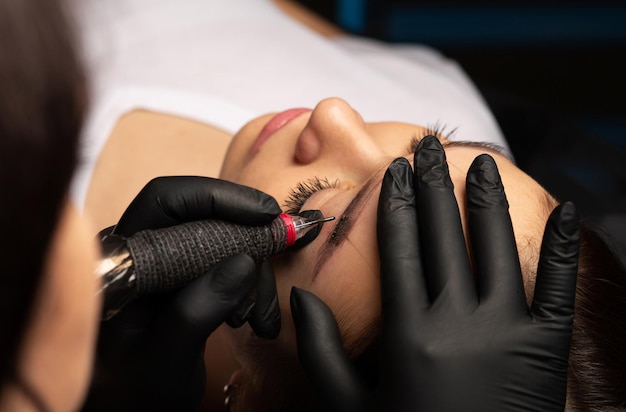 Photo maître de beauté appliquant le maquillage permanent des sourcils au salon de beauté