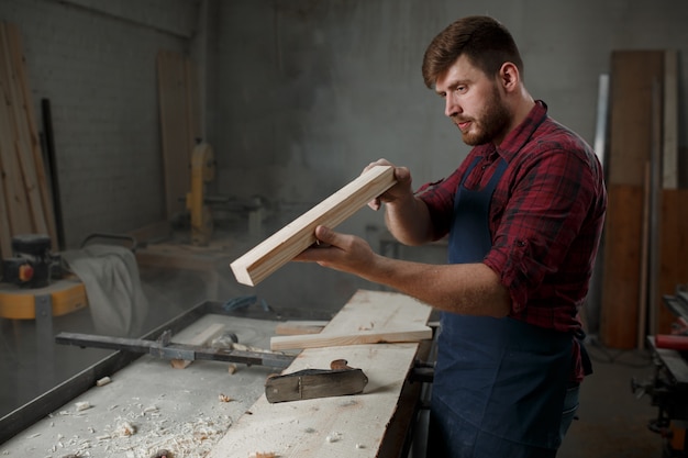 Maître charpentier en chemise et tablier dans l'atelier