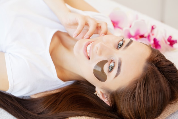 Maître et client dans un institut de beauté, patchs pour le soin sous les yeux