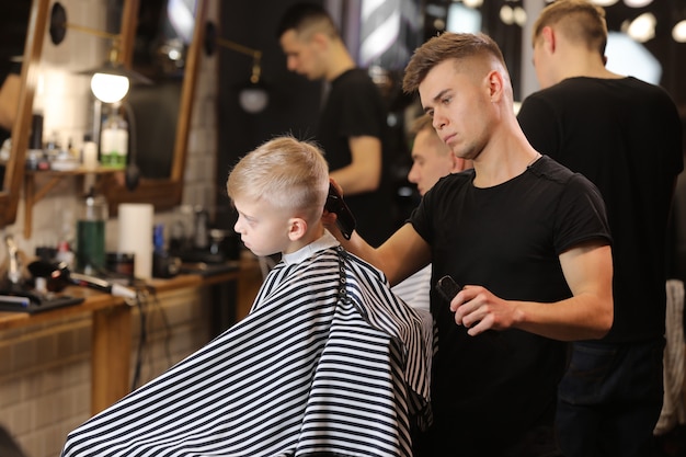 Maître coupant les cheveux d'un garçon dans un salon de coiffure