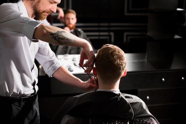 Maître coupe les cheveux et la barbe dans le salon de coiffure