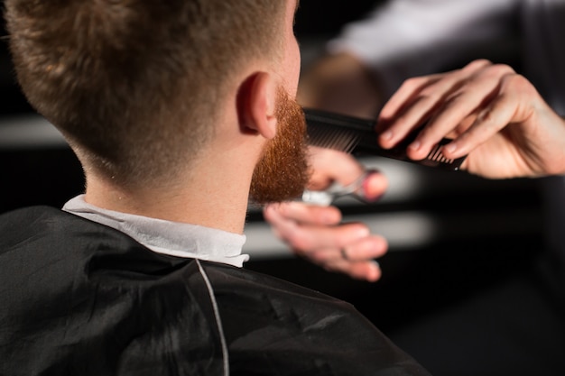 Maître coupe les cheveux et la barbe dans le salon de coiffure