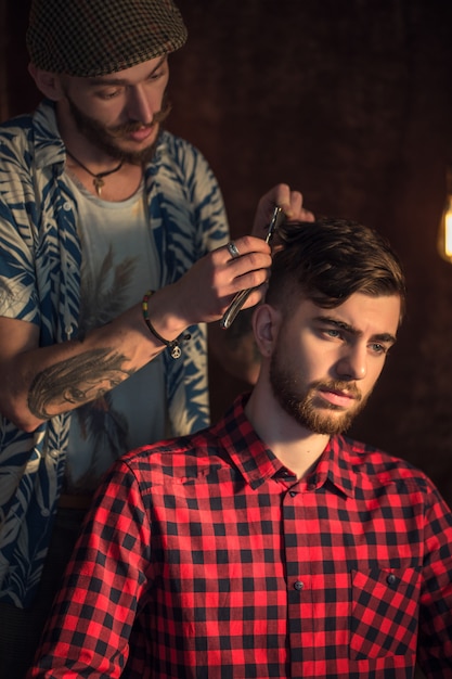 Photo maître coupe les cheveux et la barbe des hommes