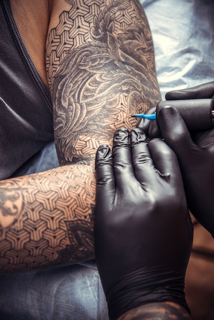 Le maître du tatouage crée un tatouage dans le salon.
