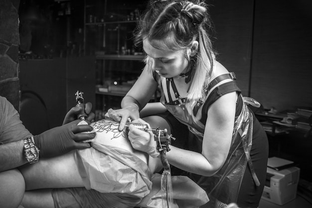 Le maître du tatouage crée un tatouage dans le salon.