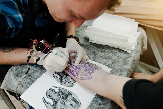 Le maître du tatouage fait un tatouage pour un rocker au salon de tatouage