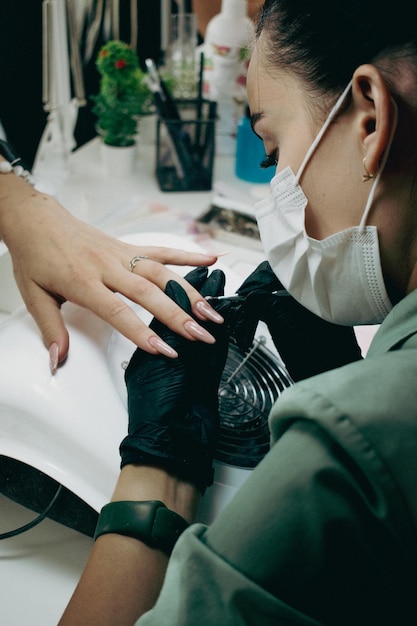 Le maître de manucure couvre les ongles avec du gellacquer dans un salon de beauté Soins professionnels des mains Le concept de soins des mains