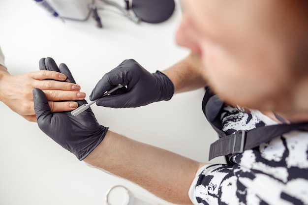 Maître de manucure faisant des soins des ongles pour le client en studio de travail