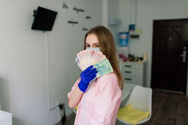 Maître de manucure féminine dans un salon de beauté avec masque de protection tenant de l'argent et souriant