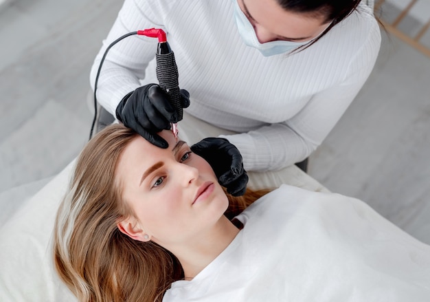 Maître de maquillage permanent tenant une machine de microblading professionnelle