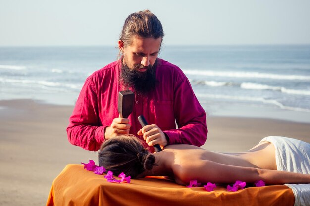 Le maître masculin fait du massage thaïlandais la physiologie de la thérapie spa Toksen au bord de la plage de l'océan