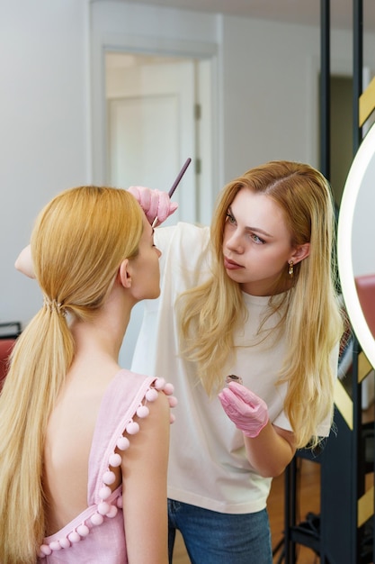 Maître des sourcils lors de la coloration des sourcils d'un client dans un salon de beauté