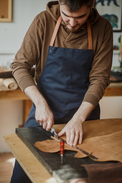 Maître tanneur coupe un morceau de cuir en atelier