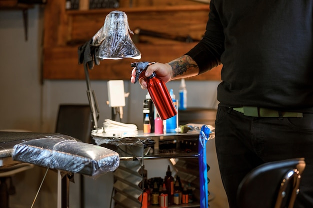 Le maître de tatouage caucasien barbu professionnel travaille dans un studio atmosphérique confortable