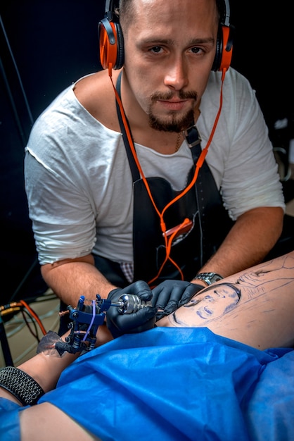 Un maître tatoueur démontre le processus pour se faire tatouer dans un salon de tatouage