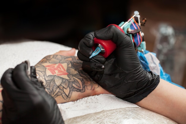 Le maître tatoueur dessine la peinture orange sur le tatouage du client