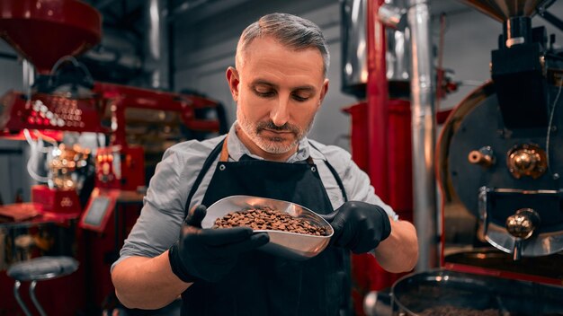 Maître de la torréfaction du café faire un bon café sur la machine moderne pour la torréfaction du café Vue rapprochée