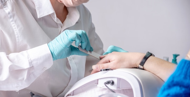 Le maître traite les ongles du client avec une lime à ongles