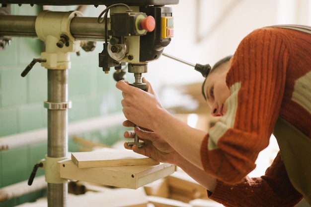 Le maître travaille sur la machine à percer dans l'atelier de menuiserie