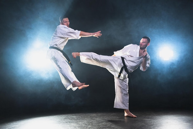 Des maîtres d'arts martiaux sur un fond sombre, des combattants forts en kimono blanc pour les arts martiaux du karaté.