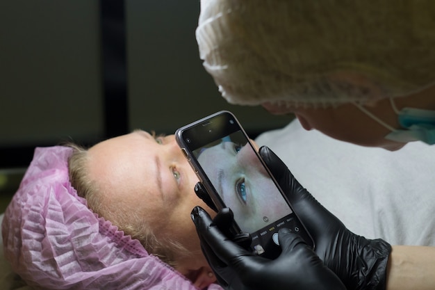 Les maîtres de la beauté réalisent un maquillage permanent des yeux avec leurs mains Le microblading est réalisé à l'aide d'une manip