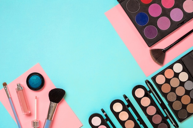 Make up essentials set de pinceaux de maquillage professionnels crèmes et ombres dans des pots sur fond bleu