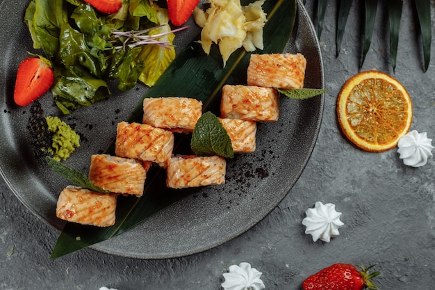 Photo maki sushi - un rouleau de fromage à la crème, de fraises, d'avocat et de saumon frit. rouleaux de sushi de saison d'été.