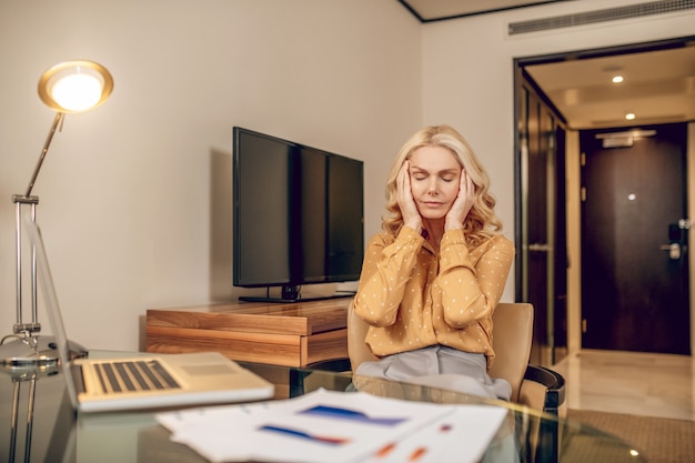 Mal de crâne. Femme d'affaires élégante blonde à la fatigue après une dure journée de travail