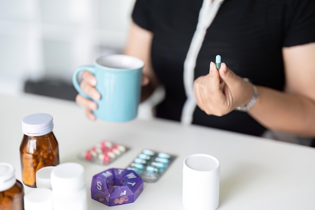 Photo malade femme tient la pilule à la main versant des capsules et du verre prend des suppléments analgésiques médicaments soins de santé concept de traitement des maux de tête