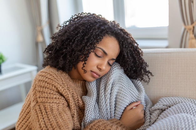 Malade jeune femme africaine se sentant froide couverte d'une couverture s'asseoir sur le lit malade fille noire frissonnant le réchauffement climatique à la maison enveloppé de plaid pas de problème de chauffage central fièvre température grippe concept