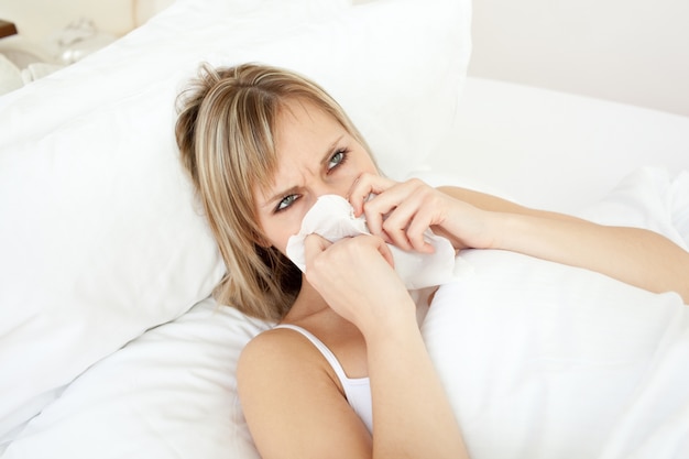 Malade jeune femme soufflant allongé sur son lit