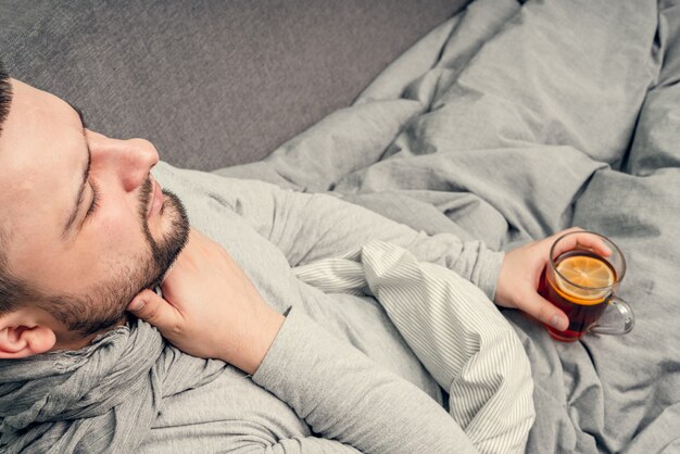 Maladie. Bravo à la maison. Un jeune homme est malade, est soigné à domicile. Se mouche dans une serviette, nez qui coule. Infection, épidémie, porteur de bacilles.