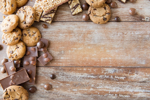 malbouffe, bonbons et concept de mauvaise alimentation - gros plan de bonbons, chocolat, muesli et biscuits sur assiette