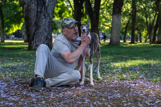 Un mâle adulte avec un lévrier à l'extérieur