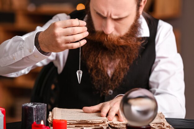 Mâle diseuse de bonne aventure avec livre et pendule à table