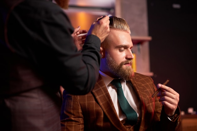 Mâle élégant profiter de la coupe de cheveux chez le coiffeur