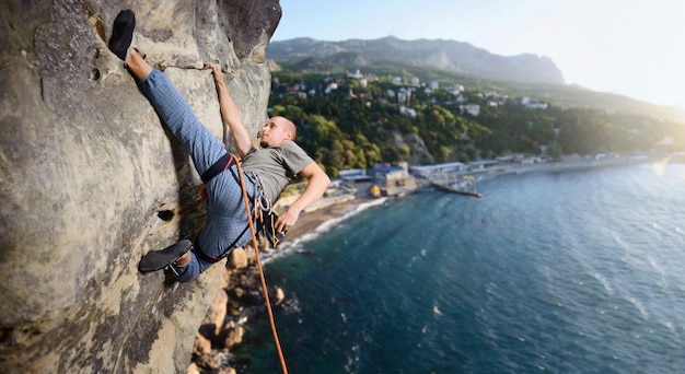 Mâle grimpeur faisant difficile monter sur la falaise en surplomb