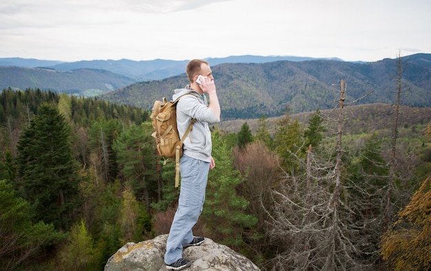 Mâle grimpeur avec sac à dos brun sur le sommet du rocher