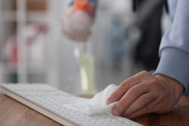 Mâle main essuyant le clavier de l'ordinateur avec serviette antiseptique close-up