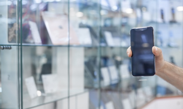 Mâle main montrant un smartphone en magasin d'électronique.