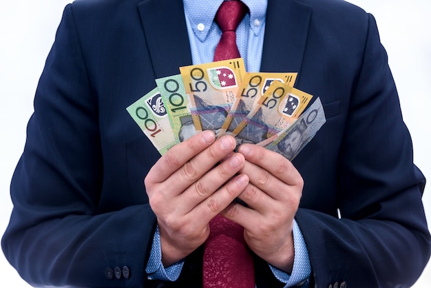Mâle main offrant des billets en dollars australiens sur blanc