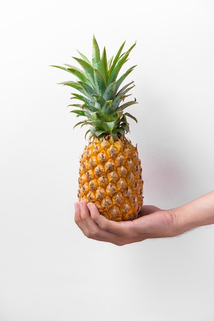 Mâle main tenant un ananas isolé sur blanc.